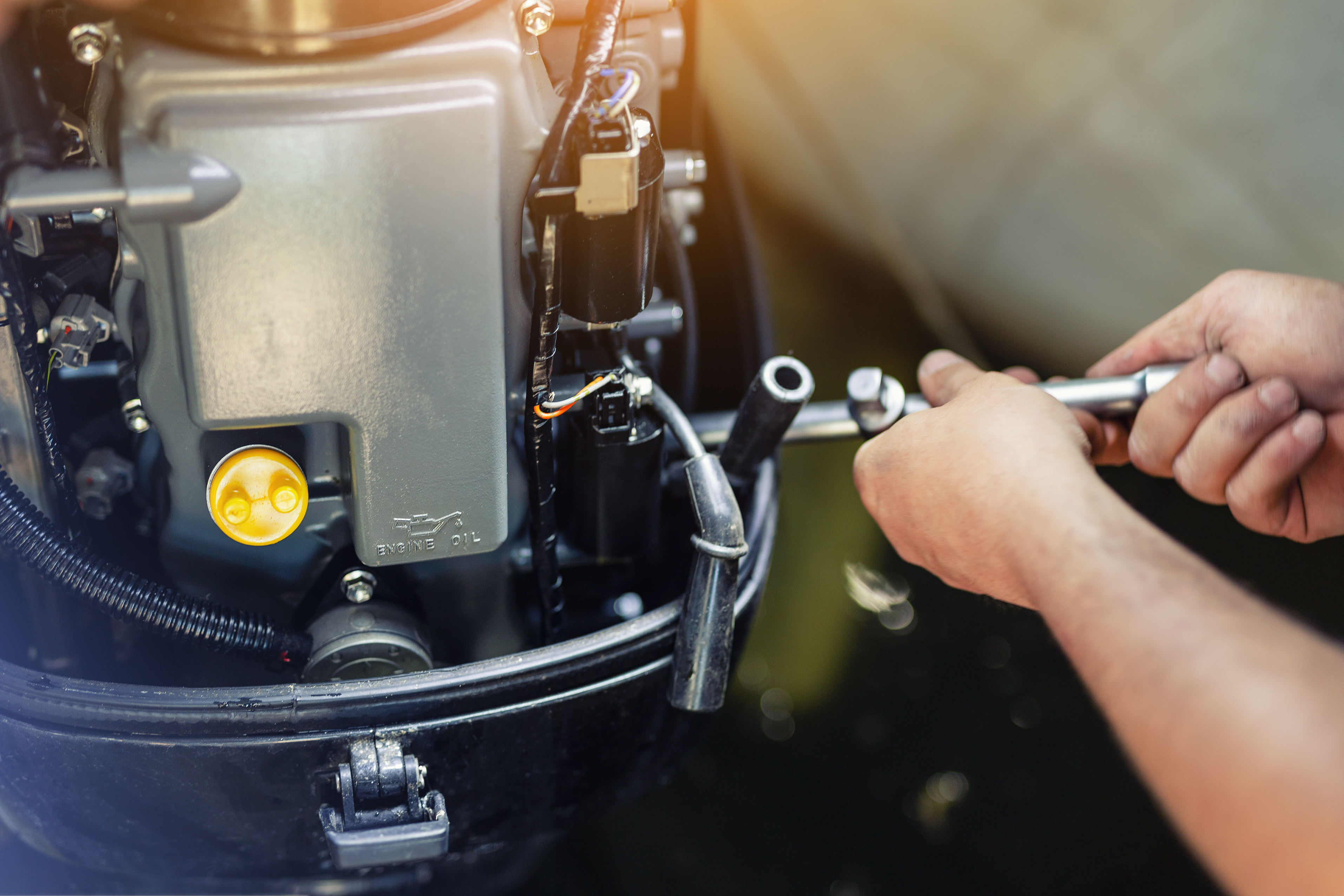 Close-up of hands processing a boat outboard motor, an important part of boat winterization. 