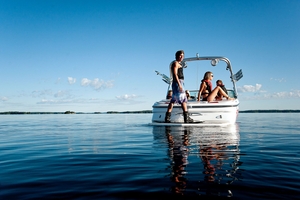 The back of a boat with a man standing on a wakeboard, port vs. starboard concept.