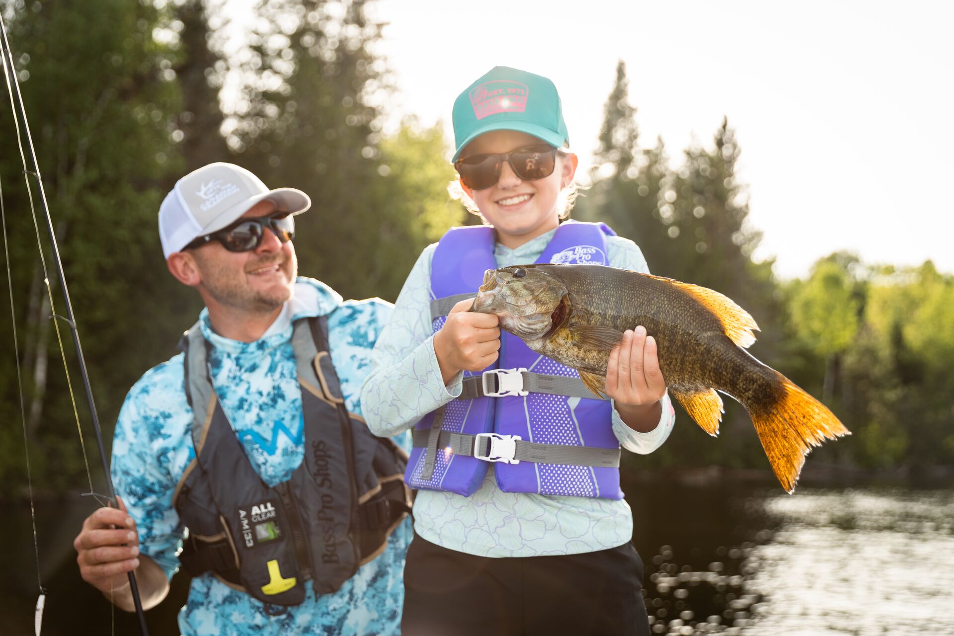 Child shows off fish next to man, use a trolling motor concept. 